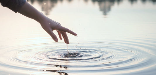 Hand gently touching calm water surface - symbolizing emotional balance and the calming effect of lithium orotate, Axis BioLabs.